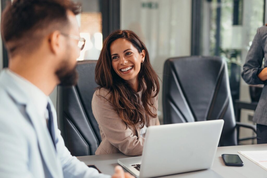 Happy businesswoman wearing blazer and smiling during discussion at meeting in office